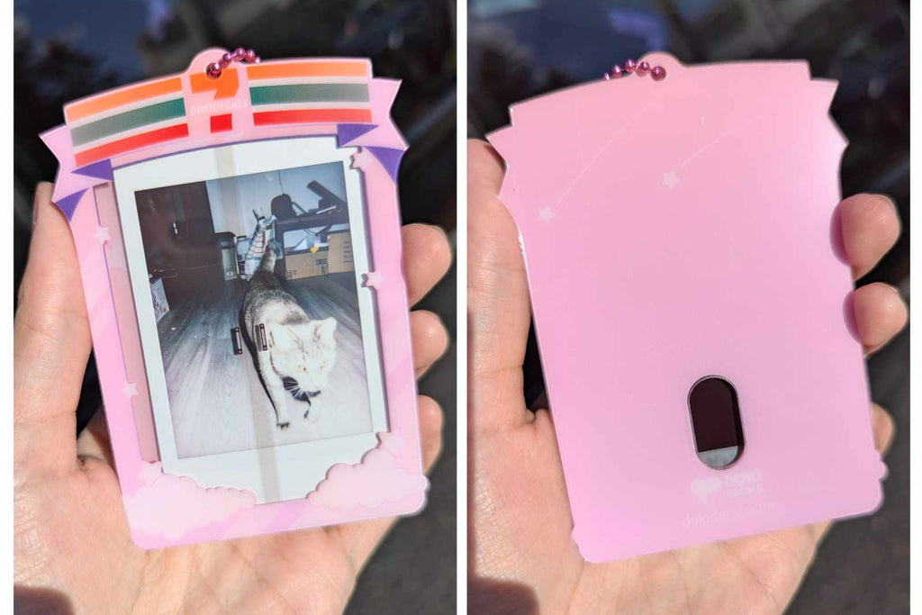 Pink photo frame with a small picture inside, held in a hand.