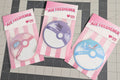 Three air freshener packages with pink and white striped design on a grid background